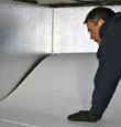 A contractor installing TerraBlock™ floor insulation in a Lake Toxaway crawl space